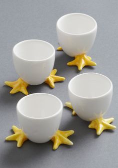 four white cups with yellow stars on the rims and one cup has three smaller ones