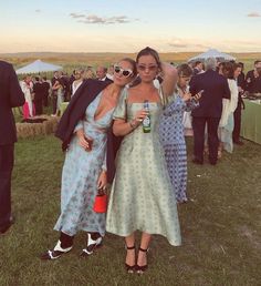 two women standing next to each other in front of a group of people at an outdoor event