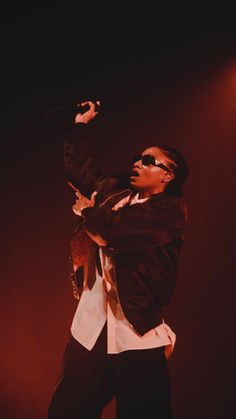 a man standing on top of a stage with his arms in the air and wearing sunglasses