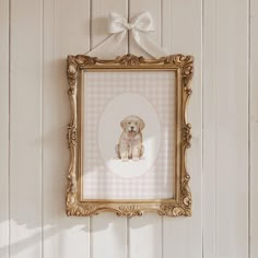 a golden frame hanging on the wall with a pink and white checkered dog in it