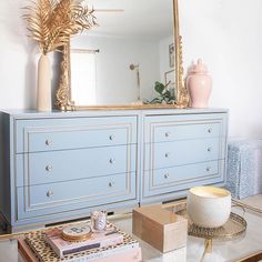 a blue dresser with gold accents and a large mirror on it's sideboard