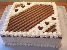 a square cake with white frosting and chocolate hearts on the top is sitting on a table