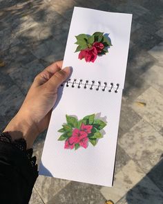 a hand holding a notepad with stickers on it next to a paper flower