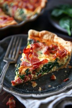 a slice of quiche with bacon and spinach is on a plate next to a fork