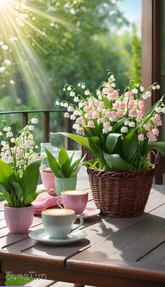 some pink and white flowers are sitting on a table with coffee cups, saucers and spoons