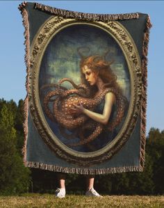 a woman standing in front of a painting on the ground with her arms wrapped around an octopus