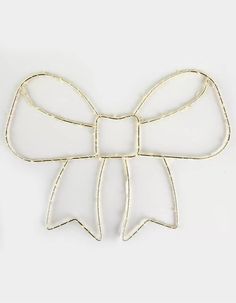 a metal bow brooch sitting on top of a white table