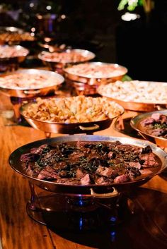 a table topped with lots of different types of food on top of metal pans