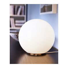 a white light sitting on top of a wooden table next to a book shelf and bookshelf