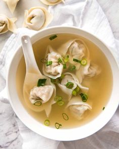 a white bowl filled with dumplings and green onions