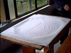 a person standing in front of a window next to a white sheet on a table