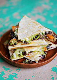 three tortillas stacked on top of each other in a wooden bowl with green and blue wallpaper