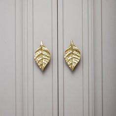 a pair of gold colored leaves on a white door