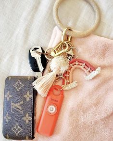 an orange keychain is sitting on top of a pink blanket next to some keys