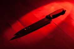 a knife sitting on top of a wooden table next to a red light in the dark