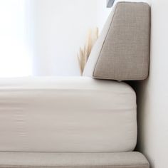 a close up of a bed with a pillow on it's headboard and a window in the background