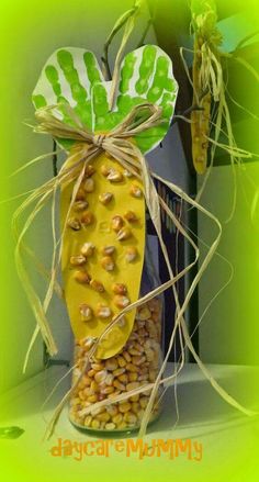 a glass jar filled with corn on top of a table next to a green plant