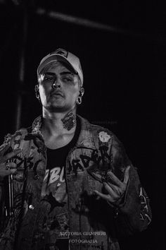 black and white photograph of a man with tattoos on his face holding a microphone in front of him