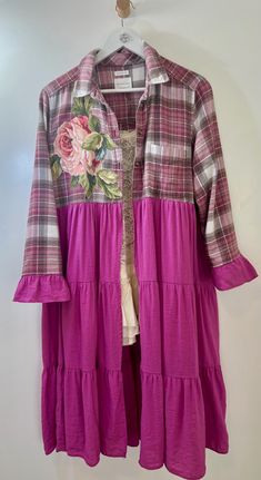 a pink dress hanging on a hanger in front of a white wall with flowers