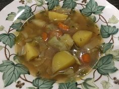 there is a bowl of soup with potatoes and carrots on the plate, ready to be eaten