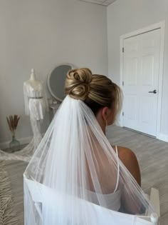 a woman with a veil on her head sitting in front of a mannequin