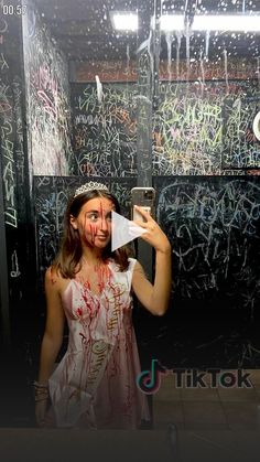 a woman taking a selfie in front of a mirror covered in paint and writing