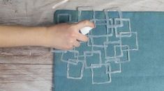 a person is using a spray bottle to decorate a piece of fabric with squares and rectangles on it