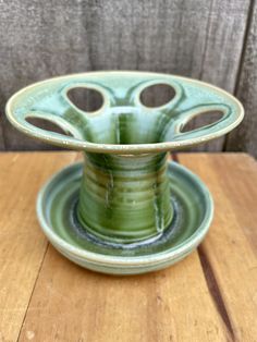 a green vase sitting on top of a wooden table