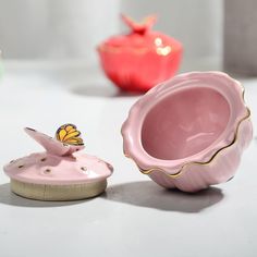 a pink vase sitting on top of a white table next to a small yellow butterfly