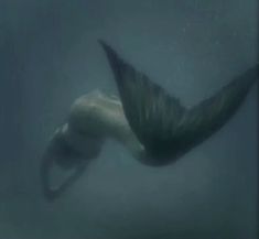 an underwater view of a man swimming in the water with his arm extended out to catch something