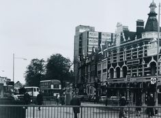 an old black and white photo of people walking on the sidewalk in front of buildings