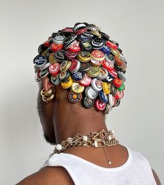 a woman wearing a white tank top has a bunch of bottle caps on her head