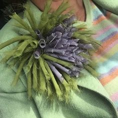 a close up of a person wearing a green sweater and holding a flower in their lap