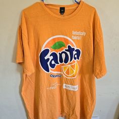 an orange t - shirt hanging on a wall with the name fanta printed on it