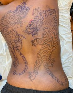 the back of a man with tattoos on his body and two tigers on his back