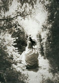 a woman in a long dress is walking down a path through the woods with trees