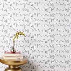 a table with a vase on top of it next to a wallpapered wall