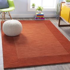 an orange rug with a white ball on the floor in front of a yellow chair