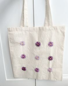 a white bag with purple flowers on it hanging from the side of a wooden door