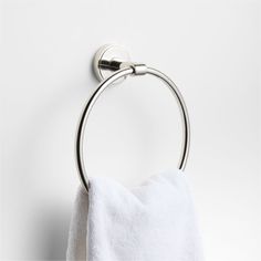 a towel hanging on the wall next to a toilet paper roll and a metal ring