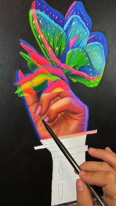 a person holding a paintbrush and drawing with colored pencils on a piece of paper