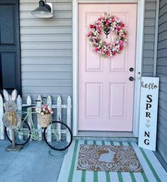 a bicycle parked in front of a pink door with a wreath on it's side