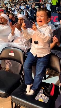 a young boy sitting on top of a chair in front of an audience