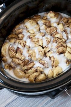 a crock pot filled with cinnamon rolls and cream