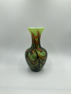 a green and brown vase sitting on top of a white table