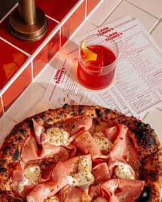 a pizza sitting on top of a table next to a drink