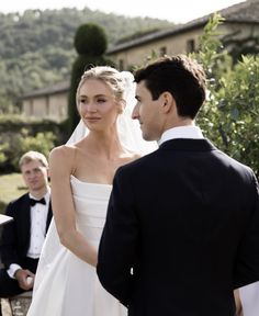 a man and woman standing next to each other in front of a wedding ceremony venue