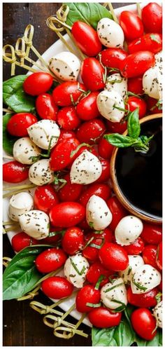 tomatoes and mozzarella on a platter with basil sprinkled around them