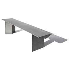 a concrete bench sitting on top of a white floor next to a metal wall mounted shelf