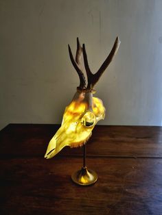 a deer's head is sitting on top of a glass vase with yellow liquid in it